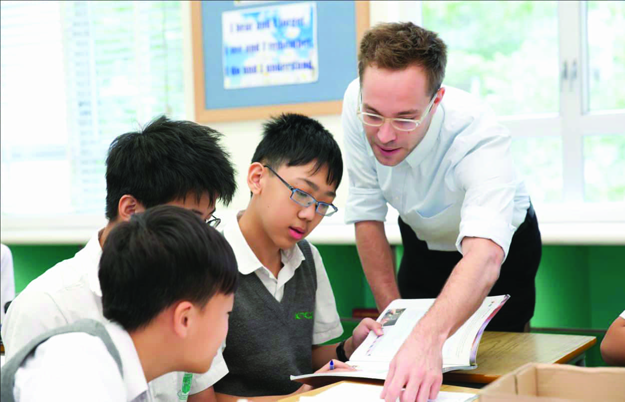 A TEFL teacher helping high school students with the task in English